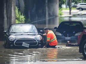 Un opérateur de dépanneuse intervient auprès de véhicules submergés dans un passage souterrain à l'angle de Parkside Drive et Lake Shore Blvd., après que de fortes pluies ont provoqué des inondations, à Toronto, le 16 juillet 2024.