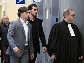 Les anciens hockeyeurs des Tigres de Victoriaville, Nicolas Daigle, à gauche, et Massimo Siciliano, suivent l'avocat de la défense Michel Lebrun, à droite, hors de la salle d'audience après avoir plaidé coupable, le mercredi 11 octobre 2023, à Québec.