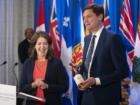 Le premier ministre de la Colombie-Britannique, David Eby, à droite, offre une bouteille de vin de la Colombie-Britannique à la première ministre de l'Alberta, Danielle Smith, alors qu'il s'adresse aux journalistes lors des réunions du Conseil de la fédération à Halifax, le mardi 16 juillet 2024.