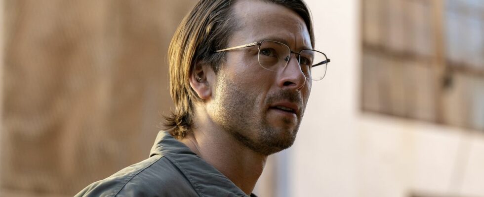 Glen Powell wearing glasses and collared shirt with long-ish hair in Netflix