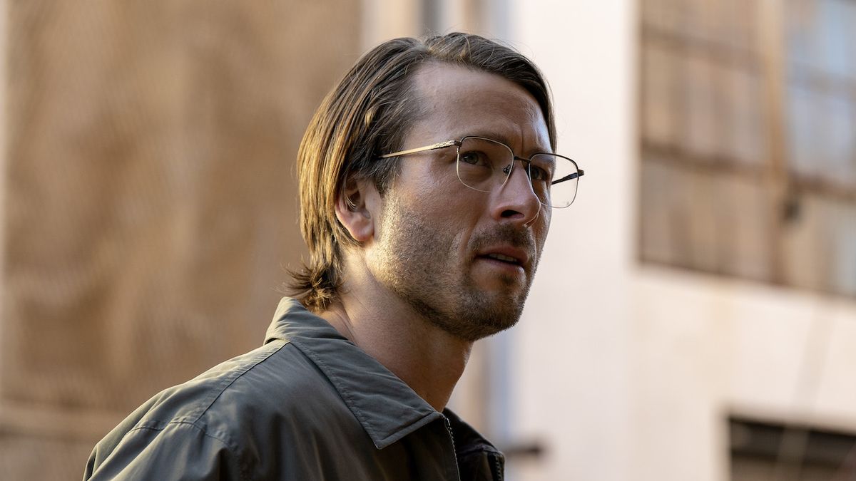 Glen Powell wearing glasses and collared shirt with long-ish hair in Netflix