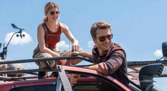 Daisy Edgar-Jones and Glen Powell smiling while working on a truck in the middle of the day in Twisters.