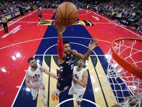 Tobias Harris des Philadelphia 76ers, au centre, se prépare à tirer entre Dean Wade des Cleveland Cavaliers, à gauche, et Georges Niang lors de la première mi-temps d'un match de tournoi de basket-ball de la NBA en cours de saison, le mardi 21 novembre 2023, à Philadelphie.