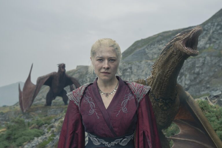 Queen Rhaenyra (Emma D'Arcy) stands near Dragonstone surrounded by dragons