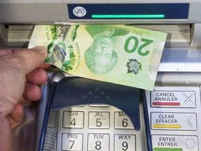 Une personne retire de l’argent d’un distributeur automatique de billets.