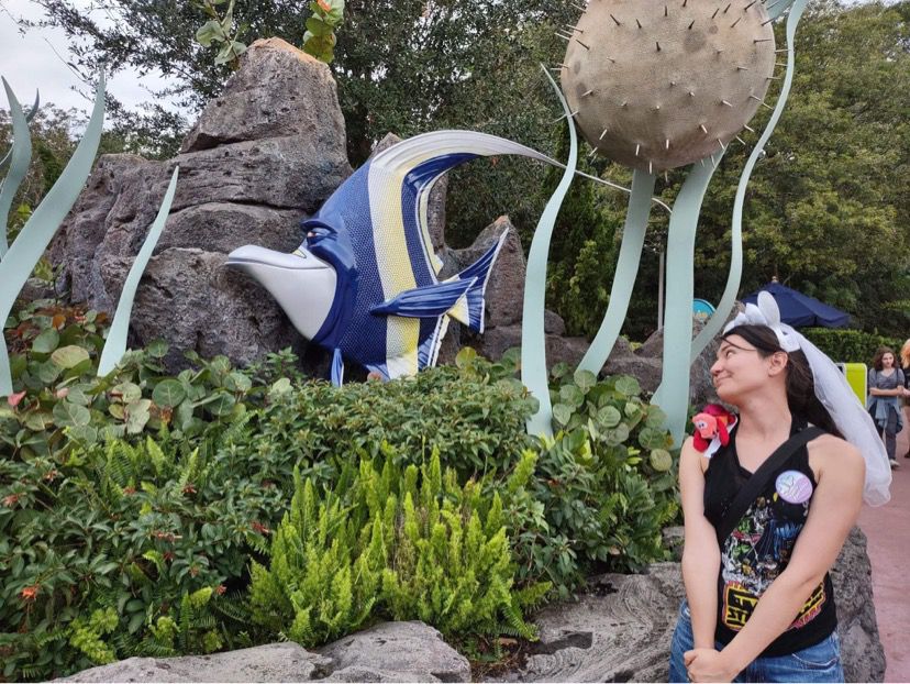 Une sculpture de Gil du film Le Monde de Nemo. Une femme portant des oreilles de Mickey la regarde avec amour.