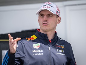 Le pilote Red Bull Racing Max Verstappen fait un geste dans le paddock.