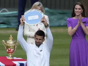 Le Serbe Novak Djokovic brandit son trophée de finaliste après sa défaite contre l'Espagnol Carlos Alcaraz en finale du simple messieurs aux championnats de tennis de Wimbledon à Londres, le dimanche 14 juillet 2024. En arrière-plan se trouve Kate, princesse de Galles.