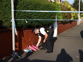 Un policier dépose des hommages floraux apportés par des sympathisants sur Hart Street à Southport, dans le nord-ouest de l'Angleterre, le 29 juillet 2024, à la suite d'une attaque au couteau.