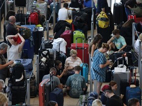 Les voyageurs attendent à un comptoir d'enregistrement à l'aéroport BER de Berlin lors d'une panne informatique qui a perturbé les services aériens ici et dans le monde entier le 19 juillet 2024 à Schoenefeld, en Allemagne.