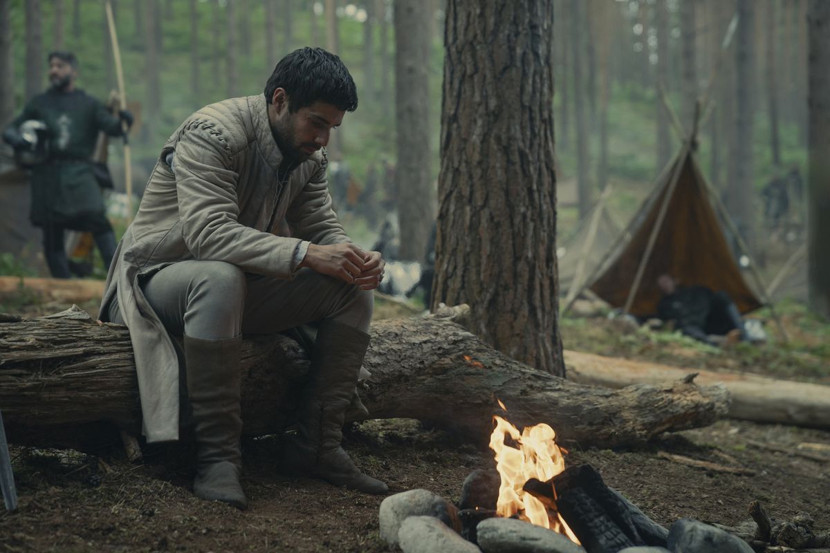 Criston Cole (Fabien Frankel) assis près d'un feu