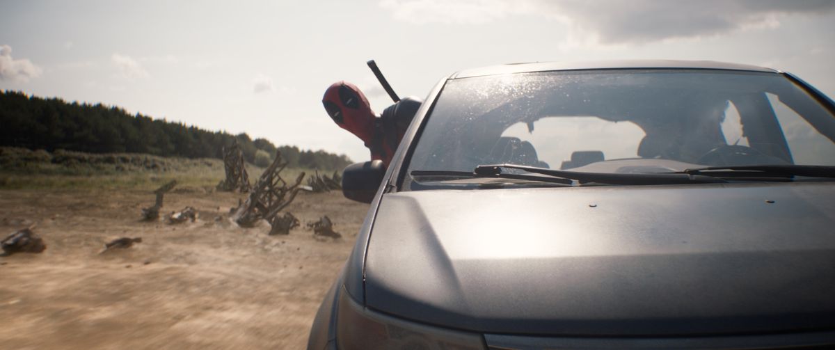 Deadpool (Ryan Reynolds) passe sa tête par la fenêtre d'une voiture roulant à toute vitesse dans le paysage désertique de The Void dans Deadpool & Wolverine