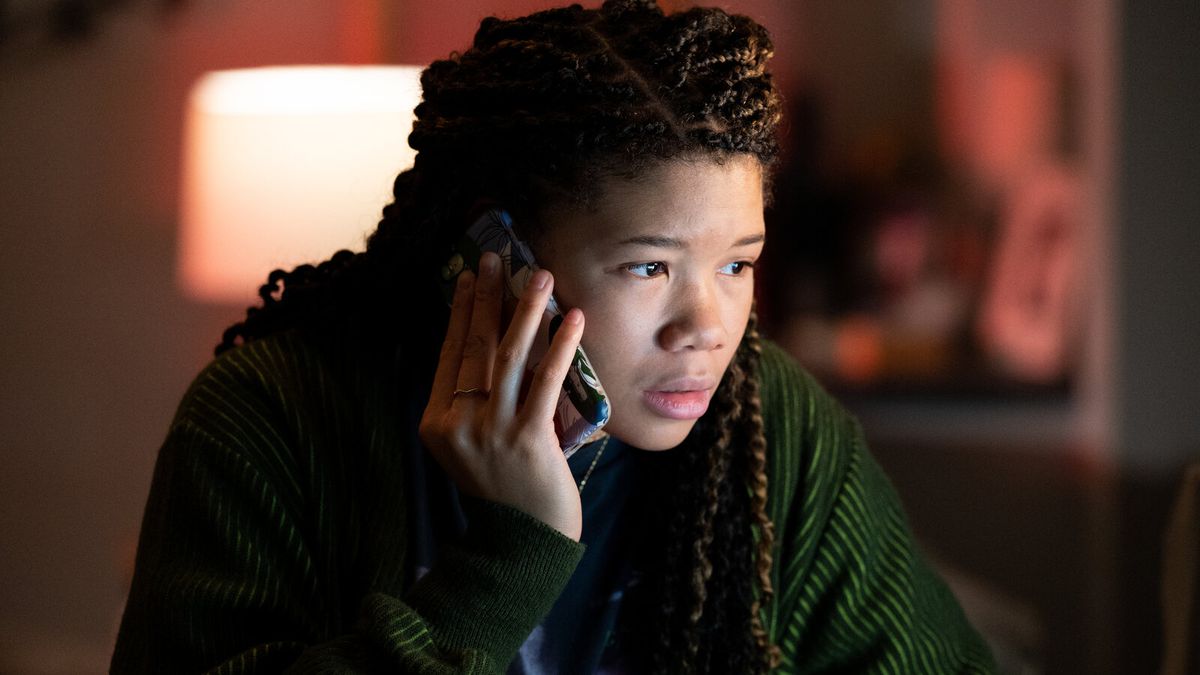 Une jeune femme (Storm Reid) aux cheveux tressés tient un téléphone portable contre son oreille tout en regardant un écran hors écran dans « Missing ».