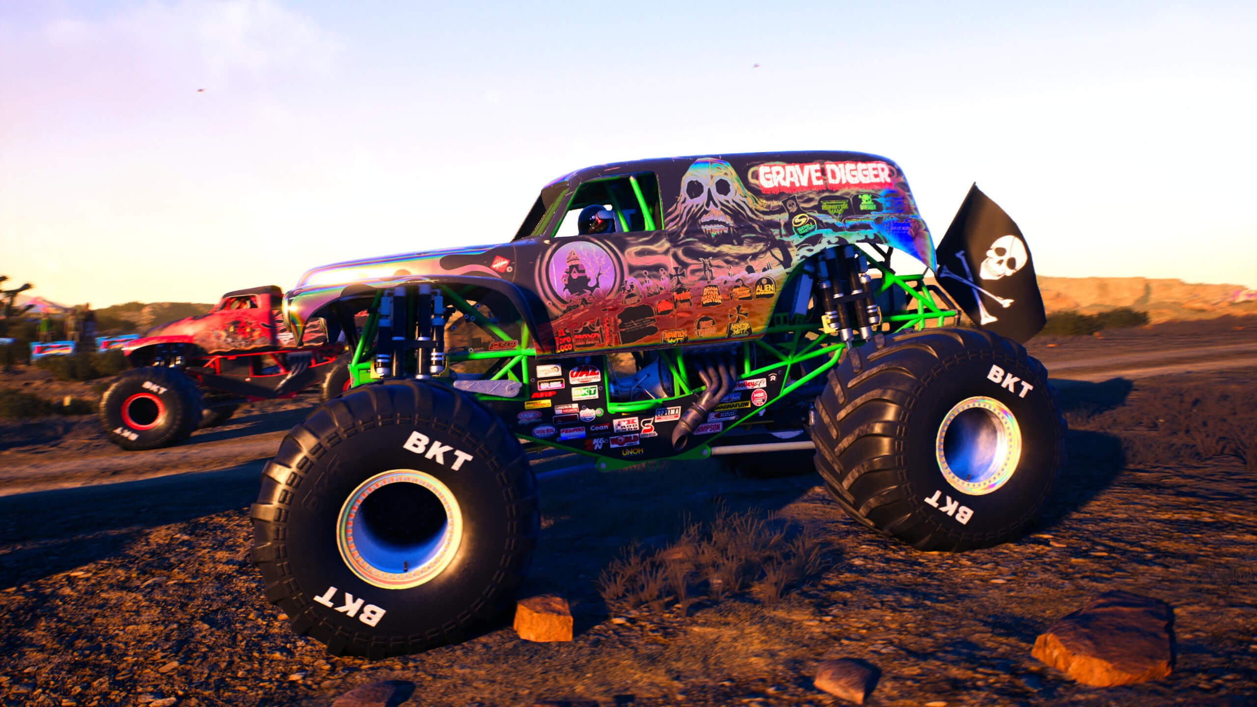 Capture d'écran de Monster Jam Showdown : Une image de Grave Digger dans sa livrée arc-en-ciel avec Vendetta en arrière-plan.