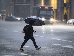 Une personne traverse la route alors qu'une forte pluie tombe à Ottawa, le jeudi 6 juin 2024. Certaines régions de l'Est du Canada s'attendent à plus de 100 millimètres de pluie d'ici la fin de semaine.