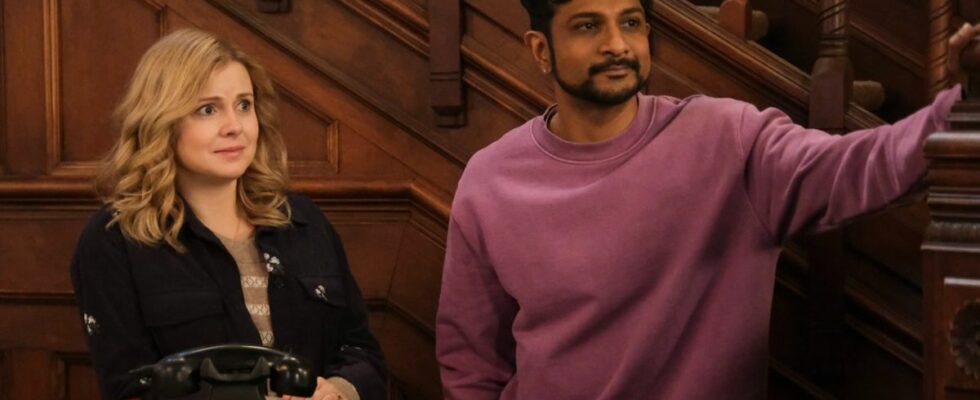 Pictured (L-R): Rose McIver as Samantha and Utkarsh Ambudkar as Jay both standing in the lobby of their in. Sam is behind the desk and Jay has his arm resting on the staircase.