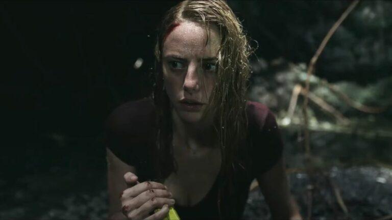 Kaya Scodelario looking concerned while holding a flashlight in an enclosed space in Crawl.