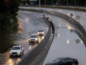 Des voitures roulent lentement dans l'eau qui déborde sur l'autoroute 40 à Sainte-Anne-de-Bellevue, sur l'île de Montréal, après que de fortes pluies ont frappé la région le vendredi 9 août 2024.