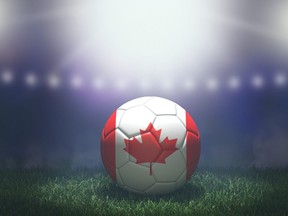 Ballon de football aux couleurs du drapeau sur un fond de stade flou et lumineux. Canada.
