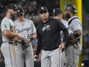 Le manager des White Sox de Chicago, Pedro Grifol, au centre, lance une balle depuis le monticule tout en se tenant avec les joueurs de champ intérieur lors d'un remplacement de lanceur lors de la 8e manche d'un match de baseball contre les Rangers du Texas à Arlington, Texas, le mercredi 24 juillet 2024.