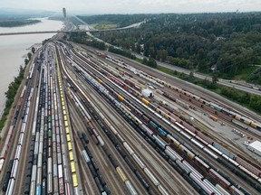 Des wagons de train sont visibles sur les voies dans une vue aérienne de la gare de triage Thornton du Canadien National alors que le pont Port Mann enjambe le fleuve Fraser, à Surrey, en Colombie-Britannique, le jeudi 22 août 2024.