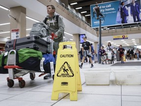 Les voyageurs manœuvrent autour des seaux pour récupérer les fuites à l'aéroport international de Calgary lundi en raison de la grêle et de fortes pluies, à Calgary, le mardi 6 août 2024.