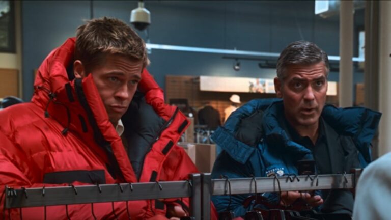 Brad Pitt and George Clooney look up with curiosity while wearing winter coats in Ocean's Thirteen.