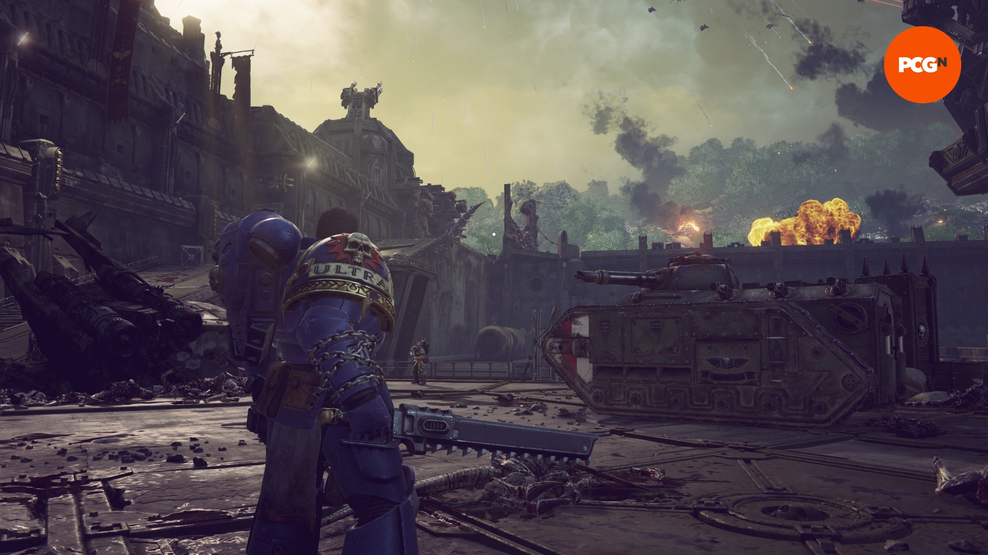 Critique de Space Marine 2 : Un homme en armure bleue se tient devant un grand char de guerre, de Space Marine 2.