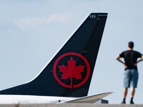 Une personne regarde un avion d'Air Canada atterrir à l'aéroport international Pierre-Elliott-Trudeau de Montréal, le vendredi 13 septembre 2024.