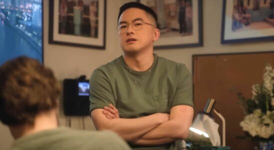 Bowen Yang stands with his arms crossed during a Saturday Night Live sketch.