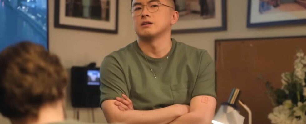 Bowen Yang stands with his arms crossed during a Saturday Night Live sketch.