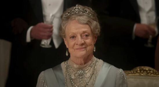 Dame Maggie Smith sits dressed in her finest smiling at a ball in Downton Abbey: The Movie.