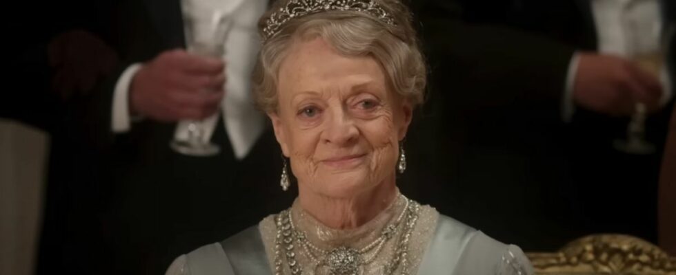 Dame Maggie Smith sits dressed in her finest smiling at a ball in Downton Abbey: The Movie.