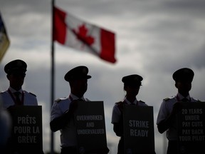 Les pilotes d'Air Canada se détachent en silhouette alors qu'ils tiennent des pancartes lors d'un piquetage d'information à l'aéroport international de Vancouver à Richmond, en Colombie-Britannique, le mardi 27 août 2024.