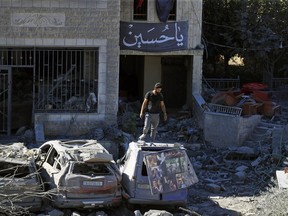 Un homme se tient au sommet d'une voiture endommagée sur le site d'une frappe aérienne israélienne à Saksakieh, au sud du Liban, le jeudi 26 septembre 2024.