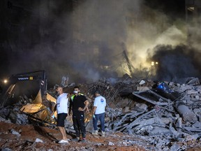 Des secouristes se tiennent sur les décombres d'un bâtiment détruit lors d'une frappe aérienne israélienne dans le quartier Haret Hreik de la banlieue sud de Beyrouth, le 27 septembre 2024.