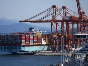 Un opérateur de grue à portique retire un conteneur d'un cargo amarré au port, à Vancouver, le mardi 16 juillet 2024.