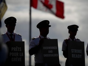 Des pilotes d'Air Canada se profilent en silhouette alors qu'ils tiennent des pancartes lors d'un piquet d'information à l'aéroport international de Vancouver à Richmond, en Colombie-Britannique, le 27 août 2024.