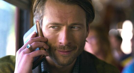 Glen Powell's Gary Johnson speaks on a phone in a close-up photo of his face in a press image for the Netflix movie Hit Man.