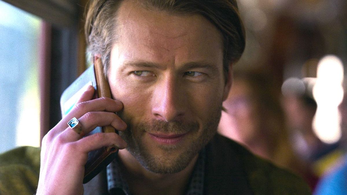 Glen Powell&#039;s Gary Johnson speaks on a phone in a close-up photo of his face in a press image for the Netflix movie Hit Man.