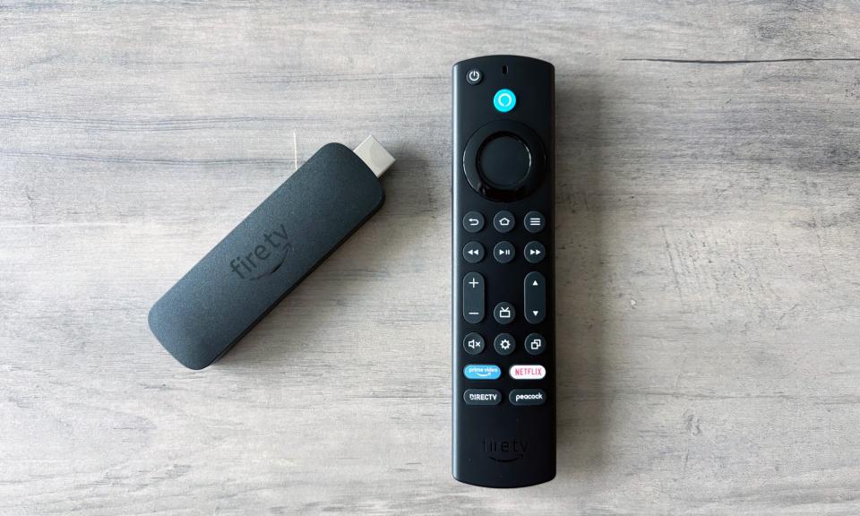 L'Amazon Fire TV Stick 4K Max repose sur une table en bois marron à côté de sa télécommande incluse.