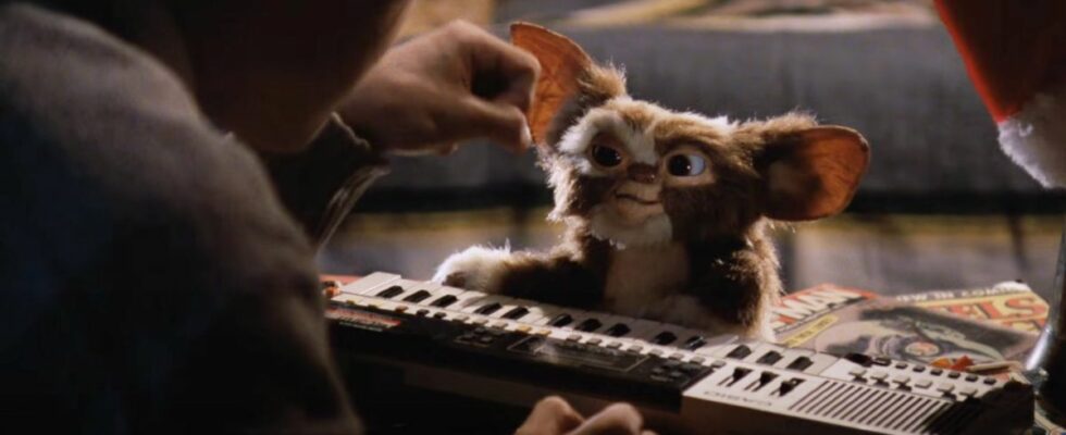 Gizmo sits smiling at a keyboard with Zach Galligan in Gremlins.