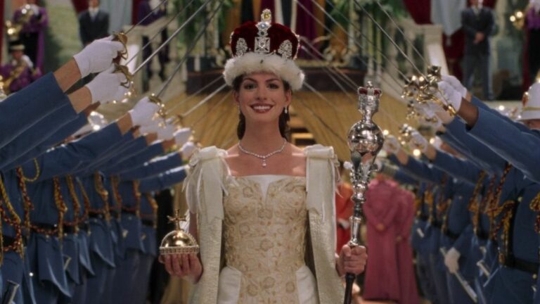 Anne Hathaway during the coronation in Princess Diaries 2. She's holding an orb in her left hand and a septer in her right and there's a crown on her head. She's smiling while soldiers stand one either side of her holding up their swords.