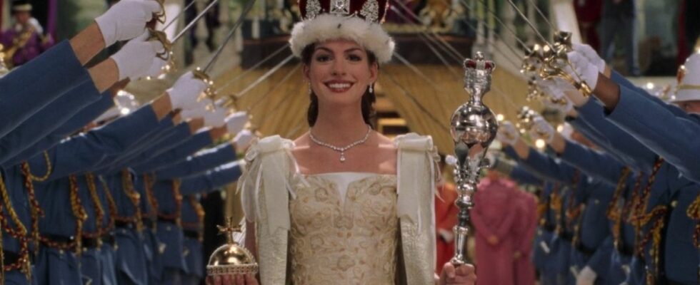 Anne Hathaway during the coronation in Princess Diaries 2. She's holding an orb in her left hand and a septer in her right and there's a crown on her head. She's smiling while soldiers stand one either side of her holding up their swords.