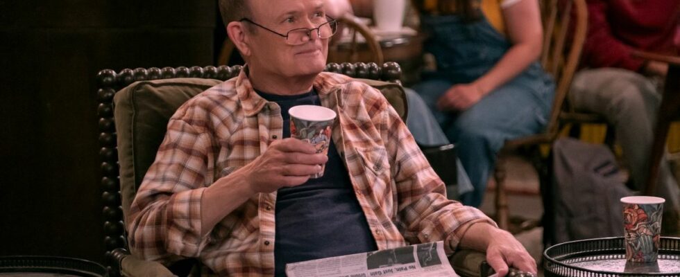 Kurtwood Smith in That '90s show with a newspaper in his lap, he's holding a coffee cup in his left hand and he's looking over his glasses.