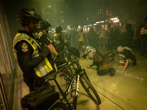 Des gens écrivent à la craie devant un bâtiment lors d’un rassemblement pro-palestinien marquant l’anniversaire de l’attaque du Hamas contre Israël à Vancouver, en Colombie-Britannique, le lundi 7 octobre 2024.