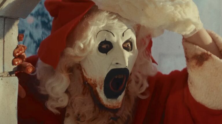 Screenshot of Art the Clown lifting the Santa Clause mask off of his face in Terrifier 3